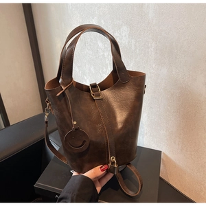 Détail du sac seau vintage marron foncé avec mini cadenas décoratif et breloque sourire