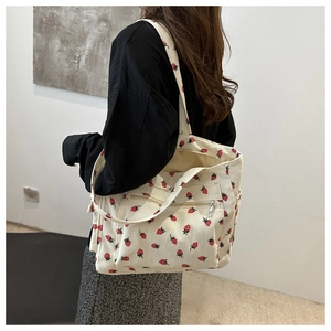 Detail of corduroy tote bag featuring red strawberry print and silver metal zipper pocket