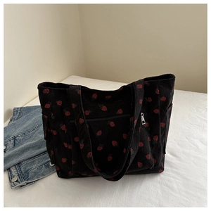 Dettaglio della borsa tote in velluto a coste nero con stampe di fragole e tasche laterali