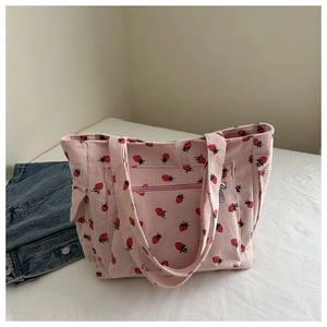 Dettaglio della borsa tote in velluto rosa con stampe di fragole e tasca con zip