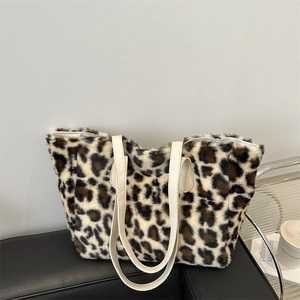 Stylish leopard print plush tote bag with white faux leather handles on a leather chair