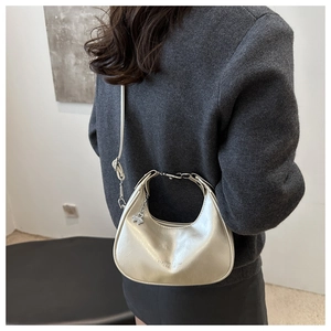 Detail of champagne gold hobo bag with metallic finish and clover charm on wool coat