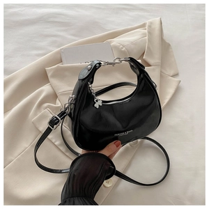 Detail of black crescent bag with metal handle and white FASHION & BAGS text on leather