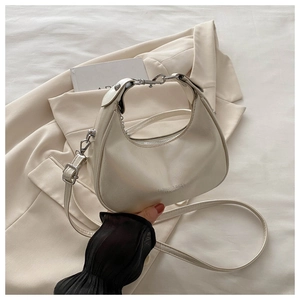 Close-up of minimalist cream crescent bag with silver zipper and leather texture