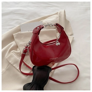 Detail of red crescent bag with silver clover charm and fashion leather text print