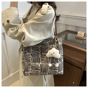 Detail of vintage striped tote bag with leather logo tag and plush cloud charm accessory