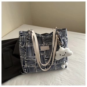 Detail of navy stripe canvas tote bag featuring white leather straps and cloud charm
