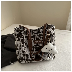 Detail of striped canvas tote bag with brown leather handles and cloud charm