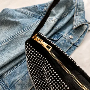 Detail eines glatten goldenen Reißverschlusses an einer schwarzen Strass-Schultertasche