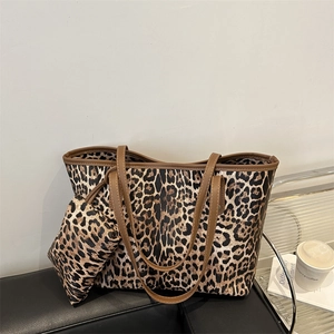 Fashion leopard print tote bag set with brown leather handles on a black sofa