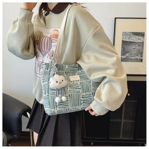 Detail of striped canvas tote bag with leather straps and a white plush cloud charm