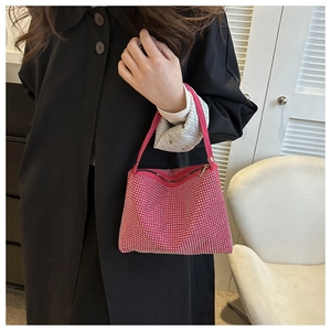 Detail einer rose roten Handtasche mit Strasssteinen, von einem Model in schwarzem Mantel gehalten