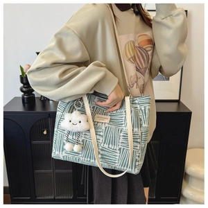 Detail of green and white striped canvas tote bag with leather tag and cloud charm