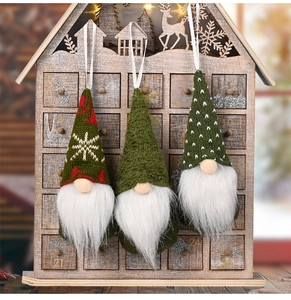 Close-up of three knitted Christmas gnome ornaments with white beards and festive hats