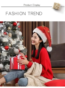Detail of red plush Santa hat with small gold bells and white pom-pom in festive setting