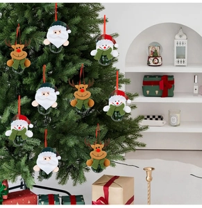 Détail de figurines en peluche Père Noël et renne avec cloches vertes sur un sapin de Noël