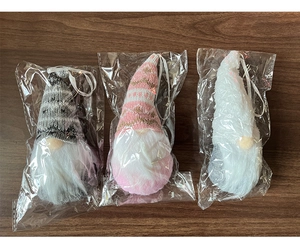 Close-up of three knitted Christmas gnomes ornaments with long white beards on wood