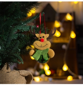Gros plan d'un pendentif renne en peluche avec cloche verte sur un sapin de Noël