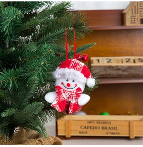 Close-up of plush snowman ornament with red bell hanging on a green Christmas tree