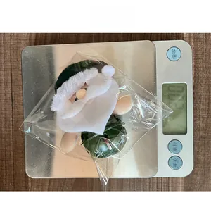 Détail d'un pendentif Père Noël avec cloche verte posé sur une balance numérique