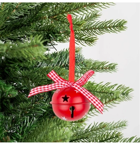 Detailopname van een rode kerstbel met ruitjesstrik aan een groene dennentak