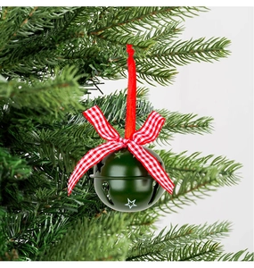 Macro-detail van donkergroene metalen kerstbel met ster-uitsparingen aan kerstboomtak
