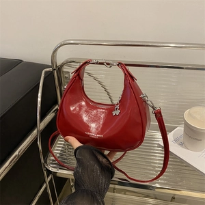 Red patent leather crescent handbag with silver clover charm and minimalist zip closure