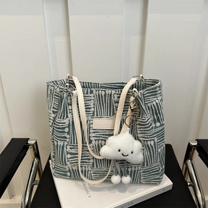 Striped green and white tote bag with cloud pendant on a chair in a bright setting