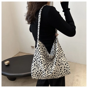 Détail d'un grand sac hobo en toile léopard porté à l'épaule par un mannequin