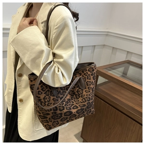 Detail of leopard print tote bag with brown leather straps shown on a female model