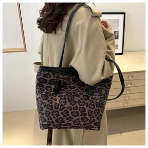 Detail of leopard print tote bag with black leather straps on model's shoulder