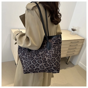 Detail view of large leopard print tote bag with black leather straps and stylish pattern