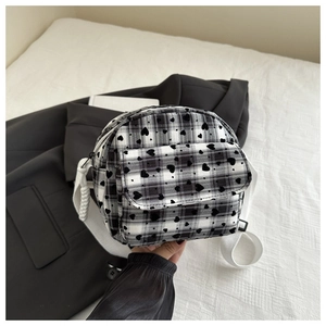 Detail of checkered crossbody bag featuring black heart prints and thick white shoulder strap
