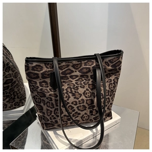 Close-up of leopard print tote bag with black leather straps on a reflective display