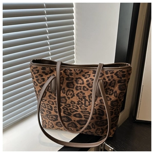 Detail of leopard print tote bag with brown leather handles on a sunlit window sill