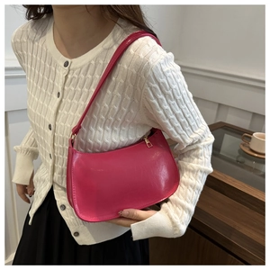 Close-up of a magenta faux leather hobo bag worn over the shoulder by a model