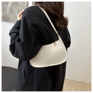 Détail d'un sac hobo demi-lune crème avec ferrures dorées porté à l'épaule