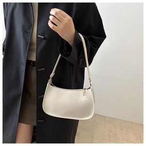 Détail du sac baguette crème avec finition en cuir verni brillant et fermeture dorée