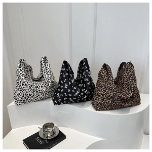 Vue détaillée de sacs cabas en toile avec motifs léopard et nœuds sur un socle blanc épuré