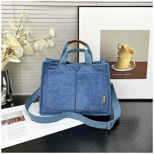 Blue corduroy tote bag with dual front pockets and brown leather trim detailing