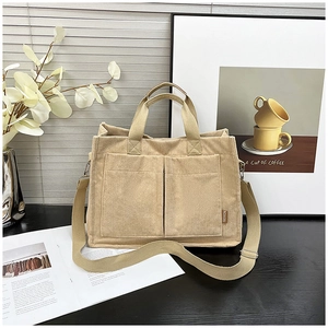 Detail of beige corduroy tote bag showing ribbed texture and two front storage pockets