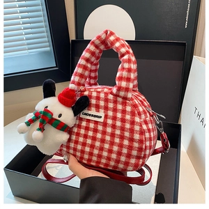 Macro detail of red gingham plush bowling bag with Christmas puppy charm in a gift box