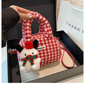 Close-up of red plaid plush bowling bag with Christmas doll charm in a gift box