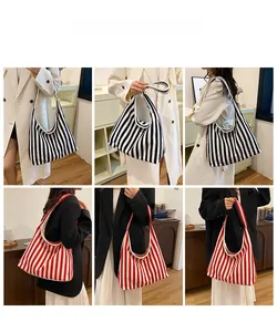 Gros plan de sacs cabas en maille rayée noir, blanc et rouge portés par un mannequin