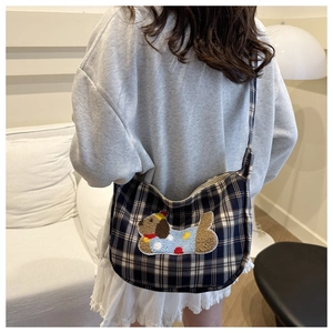 Dettaglio borsa a tracolla scozzese blu navy con ricamo cane 3D indossata dalla modella