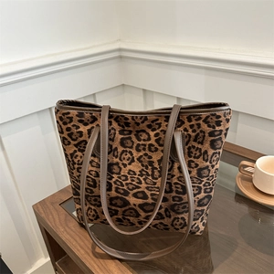 Large leopard print tote bag with brown leather handles on a modern coffee table