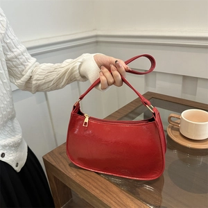Sac baguette rouge verni avec fermeture dorée et design minimaliste en forme de croissant