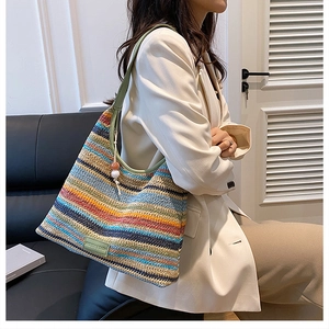 Détail d'un sac cabas en paille à rayures multicolores avec bandoulière en cuir souple