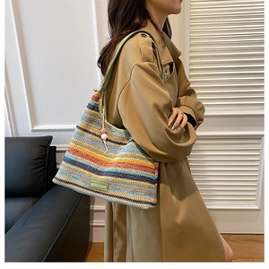 Close-up of rainbow striped woven bag featuring green leather strap and fashion label