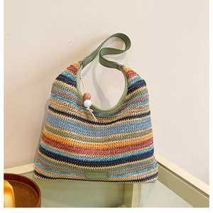 Détail du sac cabas en paille à rayures colorées avec anse en cuir vert et étiquette